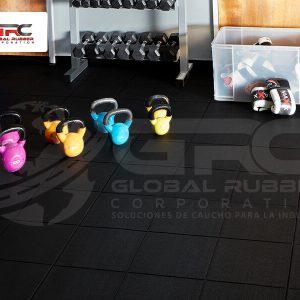 Kettlebells de colores sobre piso de baldosas de caucho negras en un gimnasio