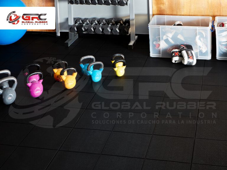 Kettlebells de colores sobre piso de baldosas de caucho negras en un gimnasio