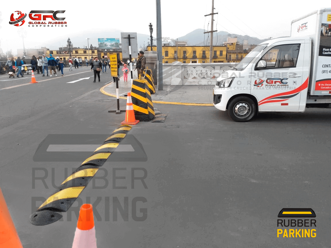Rompemuelle de caucho instalado en una vía pública con señalización de conos y un camión
