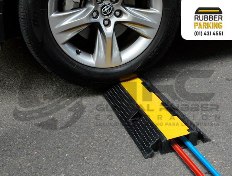 Protector de cables de caucho instalado bajo la rueda de un vehículo, con los cables protegidos en su interior